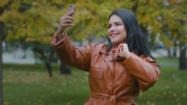 Mujer hispana de pie al aire libre mirando la pantalla hablando por teléfono utilizando la información de intercambio de videollamadas a través de la aplicación de conferencia web móvil en el blogger chica smartphone se comunica a través de webcam — Vídeos de Stock