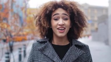 Genç ve güzel bir genç kız milenyum Afro-Amerikan kadın kıvırcık saçlı sokaklarda duruyor mevsimsel alerji hastalığından muzdarip burun virüsü hapşırıyor kağıt peçeteyle mendil temizliyor