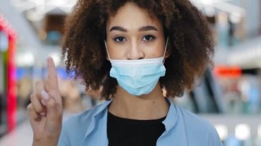 Sorumlu portre, kıvırcık saçlı hasta Afro-Amerikan bayan kameranın el sallamasına bakıyor. Tıbbi maske takmak yok. Tamam işareti, koronavirüs koruma kuralları.