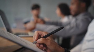 Yakın plan çok ırklı kadın el yazısı konferans odasında meslektaşlarıyla kağıt işi görüşmesi yapıyor. Tanımlanamayan çalışanlar strateji planları yazıyor. Genç kadın önemli notlar alıyor.