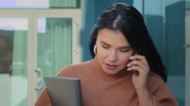 Kendine güvenen genç bir iş kadını sokak arkası ofis binasında yürüyor telefonda konuşuyor ciddi bir İspanyol kız iş telefonlarına cevap veriyor taksi konuşmaları akıllı telefon kullanıyor.