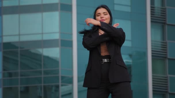 Молодая латиноамериканка-предпринимательница, уверенно стоящая на открытом воздухе на заднем дворе офисного здания, глядя на камеру, позирующую в удачной позе, чувствует удовлетворение ростом карьеры — стоковое видео