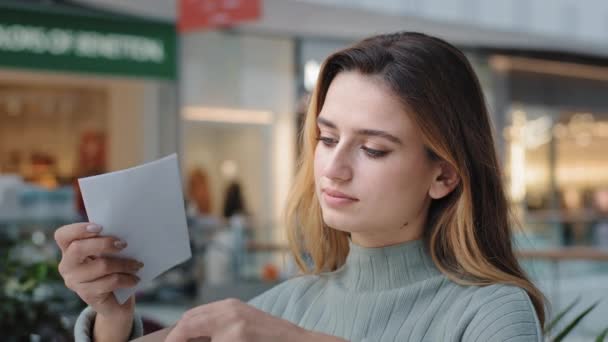 Кавказька жінка у приміщенні відкриває конверт, де читається погана новина. Документи паперового листа відчувають відчайдушну фінансову проблему боргу за вираження розчарування. — стокове відео