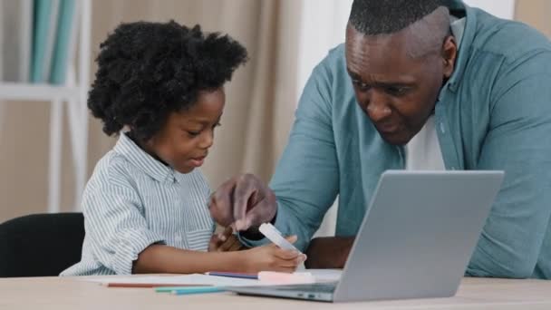 Little african american kid schoolgirl sitting at desk doing Hausaufgaben reifen Vater hilft Tochter mit Unterricht zu Hause Lehrer Tutor erklärt führt individuelle Lektion Fernunterricht während der Quarantäne — Stockvideo