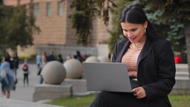 Jonge zakenvrouw freelancer student buiten zitten lezen e-mail op laptop lachen goed nieuws voelt gelukkig geniet proces surfen web op sociale netwerken chatten met behulp van computer applicatie — Stockvideo