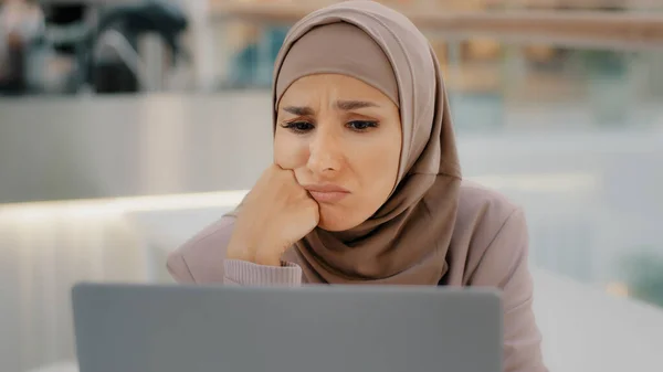 Giovane araba donna dolorosa in hijab lettura messaggio sul computer portatile ottiene cattive notizie negato prestito bancario lavoro licenziamento fallimento fallimento esame ragazza sconvolto da informazioni impreviste rende divertente espressione triste — Foto Stock