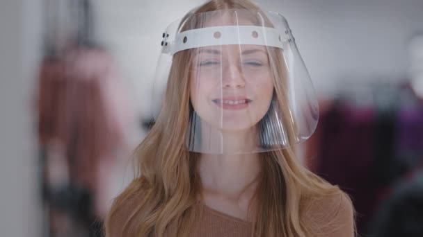 Headshot ritratto ragazza in maschera di plastica trasparente primo piano giovane donna caucasica sorridente guardando la protezione della fotocamera da infezione coronavirus dispositivo di protezione personale concetto di controllo pandemico — Video Stock