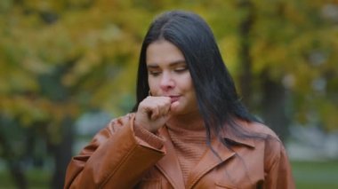 Sağlıksız genç İspanyol kadın dışarıda durup mevsimsel grip ya da kronik bronşit yüzünden öksürüyor. Boğazı ağrıyor. Soğuk algınlığına yakalanmış.