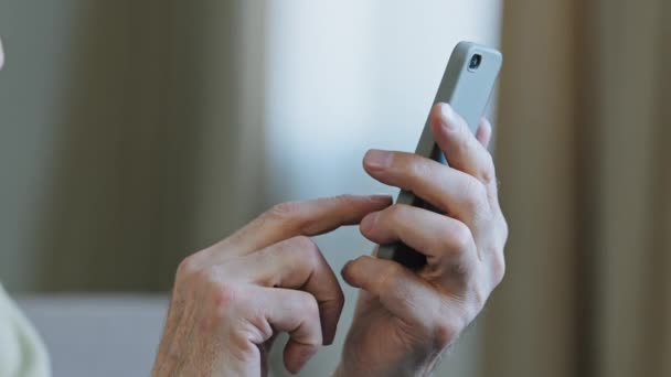 Close-up manos anciano hombre sosteniendo el teléfono escribiendo mensaje de texto haciendo uso de pedidos en línea aplicación para la comunicación remota caucásico viejo abuelo maduro disfruta de la tecnología moderna entra en el número móvil — Vídeo de stock