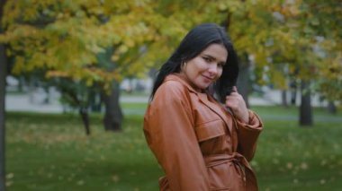 Açık havada poz veren, aşırı kilolu genç bir kadın model. Çekici yüz ifadesi olan, baştan çıkarıcı bir kıza gülümseyen, cilveli saçlarla oynayan, kıvrımlı, cilveli bir kız.