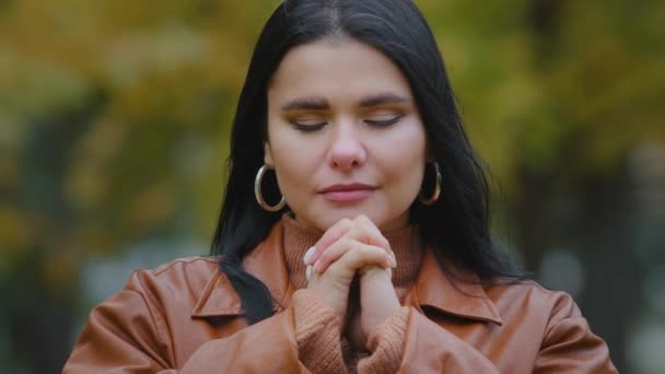 Jeune femme hispanique calme debout à l'extérieur méditant les yeux fermés tenant les mains jointes sentant des prières de paix demandant pardon grâce au rêve fait souhaiter foi religion méditation — Video