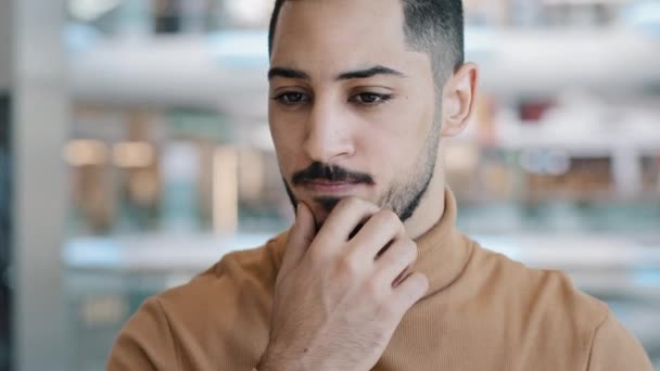 Joven hombre árabe preocupado perplejo con expresión seria cuidadosamente mantiene la mano en la barbilla pensando en resolver el problema piensa en la idea encuentra solución inventa plan de diseño plantea dedo índice sonriendo — Vídeos de Stock