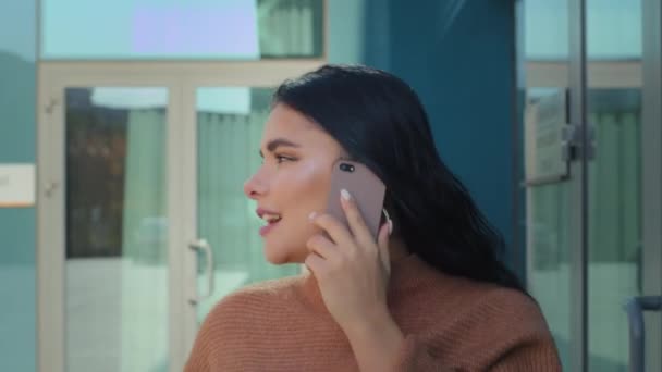 Mladý hispánec žena chůze ulice pozadí kancelář budova mluví na mobilní telefon usměvavý přátelský rozhovor objednávání služeb nebo taxi pomocí smartphone komunikace zvedání telefonních hovorů — Stock video