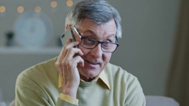 Portre gri saçlı gözlüklü yaşlı adam telefonda gülümseyen yaşlı dede konuşuyor neşeli bir şekilde cep telefonu kullanıyor iyi haberleri çocuklarla paylaşıyor evde mutlu erkek dinleniyor keyifli sohbetler.