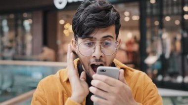 Akıllı telefonlara bakan genç adam büyük haberlerle e-posta okuyor sevinçle seviniyor online oyun kazanma başarısını kutluyor kumar bursu kazandı özel bir işe davet aldı mutlu bir teklif sunuyor