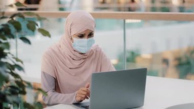 Koruyucu maske takan, tesettürlü genç bir Arap kadın kötü haber alan e-postayı okuyor. Boşanma davasında başarısız olan mali kriz sorunlarından ihraç edildiği için üzgün.