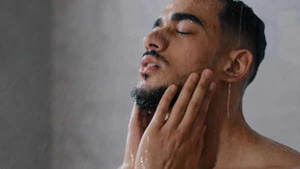 Arab indian man skäggig kille naken man tvättar huvudet med schampo tvätta håret ansikte och skägg i badrummet duscha in hemma på hotellet efter träning närbild. Brunett sköljschampo och balsam — Stockfoto