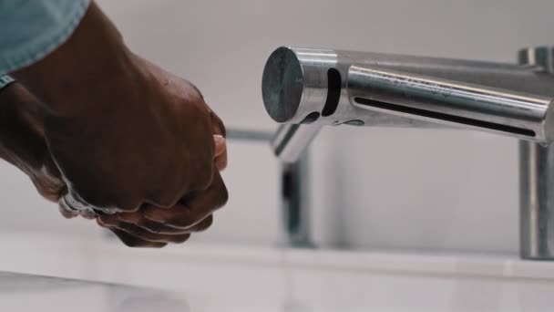 アフリカ系アメリカ人の既婚男性が公衆トイレで洗面台自動化技術を使って。近くの男性の手は、水石鹸コロナウイルス保護衛生スキンケアコンセプトで洗浄 — ストック動画