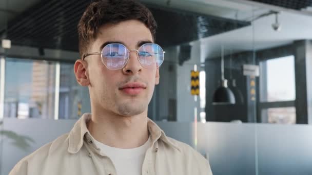 Close-up male portrait in profile caucasian guy student in glasses slowly turns his head looks at camera friendly smiling young office worker trainee company employee freelance manager posing indoors — Stock Video