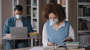 Tıp maskeli iki öğrenci üniversite kütüphanesinde sınava hazırlanıyor. Dizüstü bilgisayarlı kız kitabı okuyor. Ders kitabında doğru bilgileri arıyor.