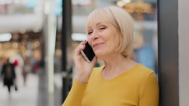 Улыбка счастливой зрелой женщины средних лет говорить по мобильному телефону делает заказ использует смартфон приятный дружеский разговор дистанционного общения старшего поколения и с использованием современных технологий — стоковое видео