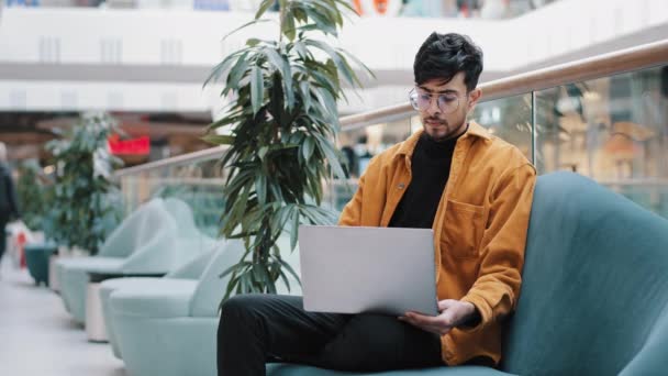 Giovane arabo serio freelance maschile in occhiali si siede guardando lo schermo del computer portatile funziona in remoto caricato nei pensieri sul lavoro pensa al problema aziendale cerca ispirazione nuove idee trova soluzione — Video Stock