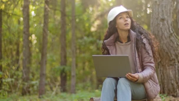 Millennial woman young experienced specialist forestry engineer environmentalist technician in hardhat checking trees entering data into laptop taking reforestation measures observing nature reserve — Stock Video