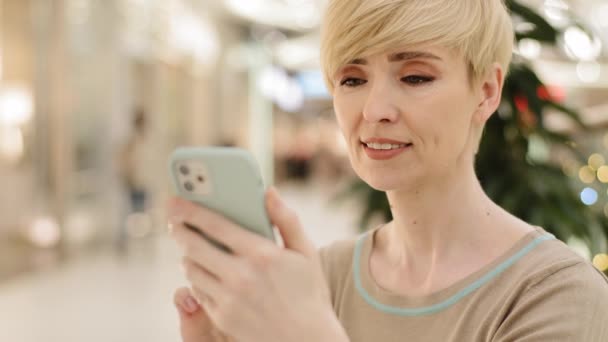 Portre olgun orta yaşlı beyaz kadın iş kadını cep telefonuyla internetten yemek siparişi veriyor sohbet uygulaması mesajı kullanarak internetten alışveriş yapıyor ve akıllı telefonlara bakıyor. — Stok video