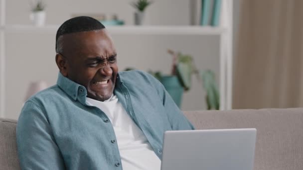 Dorosły Afrykanin amerykański człowiek siedzi patrząc na ekranie laptopa zastanawiał się śmieszne wyrażenie zamrożone czekając podziwiając ulgę radując się zwycięstwem pokazując zatwierdzony gest ulubiony zespół wygrywa mecz — Wideo stockowe