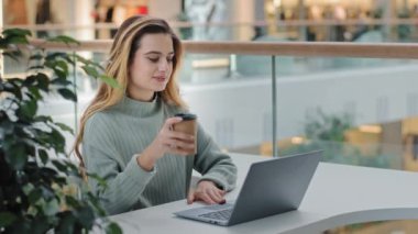 Kafkasyalı iş kadını serbest tasarımcı kadın tasarımcı kafeterya ofis alanında dizüstü bilgisayarla çalışıyor kahve çayı içip internetten ücretsiz internet alışverişi yapmayı öğreniyor.