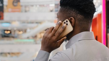 Arka planda genç Afro-Amerikan iş adamının cep telefonuyla konuşması iş görüşmelerine cevap vermesi müşteri danışmanına telefonla arkadaşlarıyla iletişim kurmasını tavsiye etmesi.