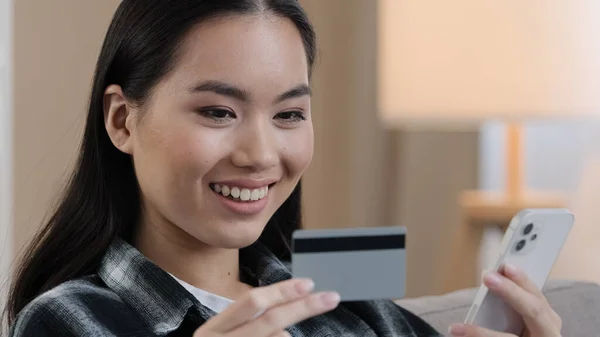 Banka kartı ve cep telefonlu Asyalı Koreli Çinli kız internet üzerinden elektronik ödeme alışverişi yapıyor. İnternet üzerinden e-ticaret rezervasyonu siparişi alıyor. — Stok fotoğraf