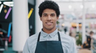 Afrikalı Amerikalı erkek işçi 20 'li yaşlarda garsonluk yapıyor. Önlüklü, küçük işletme kafesi restoran müdürü. İş yerinde gülümseyen dişlek bir portreyle kameraya bakıyor.