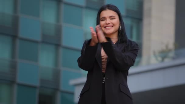 Fiatal sikeres mosolygós spanyol üzletasszony tapsoló kezét háttér irodaépület nézi kamera taps tenyér kifejező csodálatát köszöntő köszöntés jóváhagyása gratuláció ováció