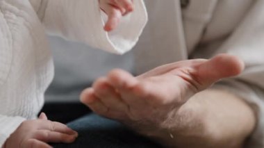Yakın plan bebek, yeni doğmuş şirin eller, el çırpma vuruşu, erkek eli baba kolu. Detaylar baba-çocuk bağı dokunuşu. Kafkas ailesi çocuk bakımı babalığı güvenlik sevgisi