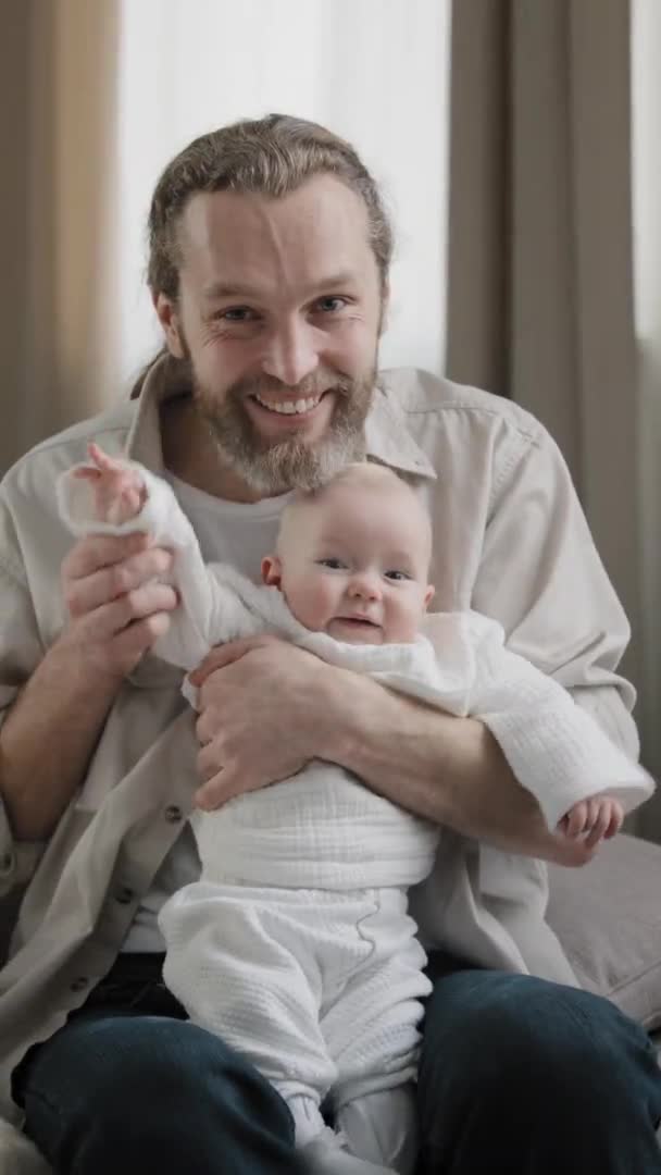 Pionowy kamera widok kaukaski szczęśliwy rodzina dorosły brodaty tata pocałunek dziecko ręka i niemowlę noworodka mała dziewczynka mały syn macha rękami powitanie cześć kamera wideo call konferencja w domu — Wideo stockowe