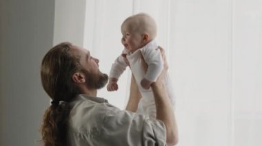 Kafkas ailesi sakallı baba baba küçük kızıyla oynuyor bebek bebek bebek bebek pencere kenarında oyun oynuyor çocuk yükseltiyor birlikte eğlenceli oyun oynuyorlar