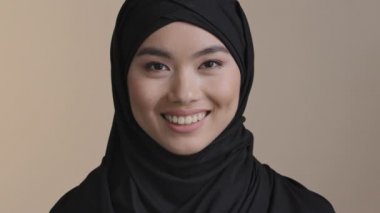 Portre gülümseyen yönetici iş kadını Asyalı Müslüman kız gündelik kıyafet giyip evdeki modern ofis işyerinde gülümseyen kameraya bakıyor. Genç bayan dişçi müşterisi dişlek gülüyor.