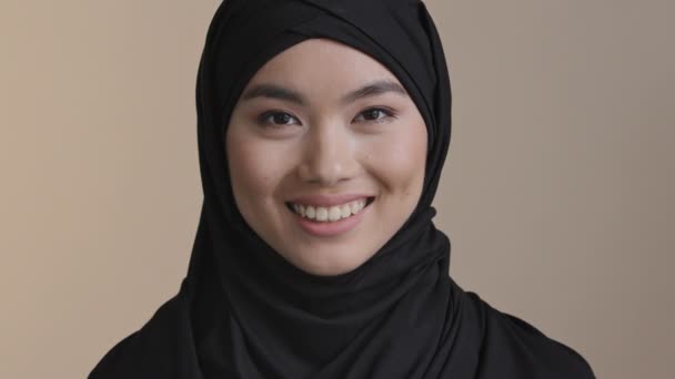 Portrait smiling executive business woman asian muslim islamic girl casual wear hijab looking at camera smile happy in modern office workplace at home. Wanita muda layanan gigi klien tertawa tottish — Stok Video