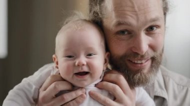 Kafkas sakallı mutlu baba ve yeni doğmuş tatlı kız evlat kameraya gülümseyen, konuşan, gülen, evde poz veren bir çocuk. Yakın plan baba web kamerasına bakarak küçük bir çocuğu kucaklıyor.