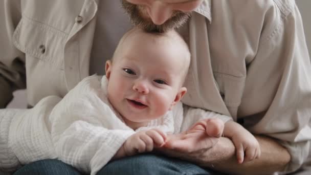 Biały brodaty ojciec tatuś łaskocze główkę dziecka brodą bawiącą się z dzieckiem w domu. Zbliżenie noworodka do twarzy niemowlęcia. Opieka rodzicielska nad opiekunem adopcyjnym — Wideo stockowe