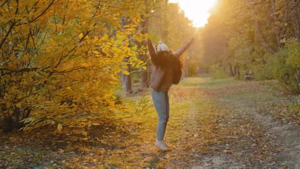 Jovem alegre menina hispânica alegre alegre andando ao ar livre no parque de outono girando pulando apreciando a natureza bom tempo no dia quente ensolarado agradável andar liberdade sente alegria se alegra se divertindo girando — Vídeo de Stock