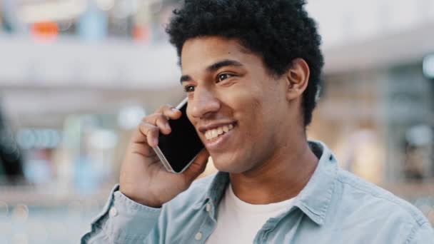 Πορτρέτο χαρούμενος Αφροαμερικανός άνθρωπος οδηγήσει ανέμελη συνομιλία στο smartphone σε εσωτερικούς χώρους απολαύσετε ευχάριστη επικοινωνία απάντηση κλήση χαμογελώντας γέλιο μοιραστείτε τα νέα με τον οικογενειακό φίλο. Τεχνική έννοια σύνδεσης Wi-Fi — Αρχείο Βίντεο
