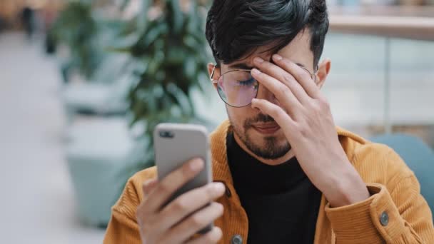 Close-up jovem triste homem árabe infeliz olhando para tela do telefone lendo e-mail sendo chocado por terríveis más notícias sentindo emoções negativas perturbado tristeza perplexidade preocupado com a perda de aviso de problema — Vídeo de Stock