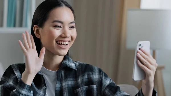 Happy friendly asian girl blogger vlogger smiling female distant woman mobile phone video call remote communication greeting waving hand talking smartphone webcam virtual conversation app online talk — Stock Photo, Image