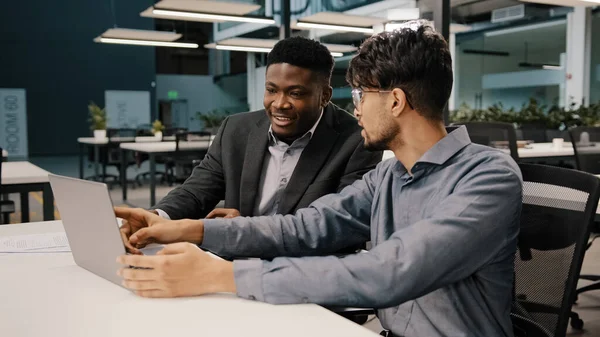 Arap erkek finansal analist iş stratejisini açıkladı. Afrikalı girişimci dizüstü bilgisayarı işaret ederek proje sözleşmesinin faydalarını gözden geçiriyor. Ofiste takım çalışması tartışması yapılıyor.