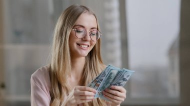 Ofiste para sayan neşeli zengin kız başarılı beyaz kadın iş kadını bir tomar para kazanıyor ikramiye maaşı olan mutlu kadın zafer muhasebe bütçesi bahsi kazanıyor.