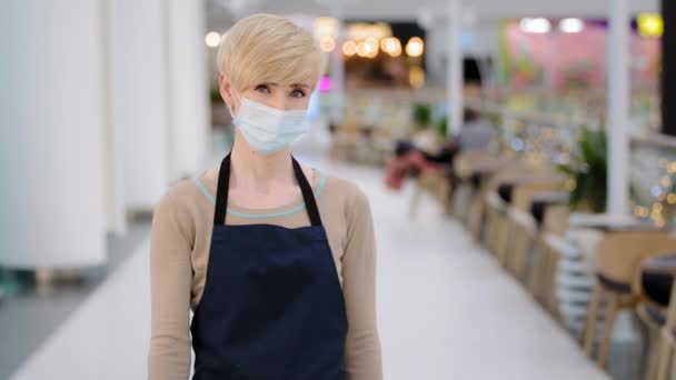 Alegre camarera caucásica camarera mujer en máscara médica invitando a los visitantes feliz vendedora en el gesto delantal bienvenida a los clientes propietario de la pequeña empresa cafetería restaurante amigable trabajador invitación — Vídeo de stock