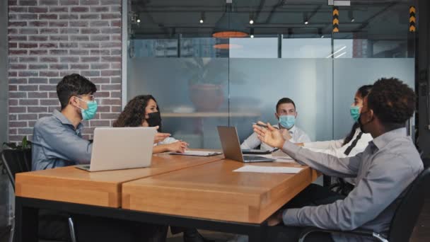 Různí zaměstnanci v lékařských maskách hádka sedí v kanceláři naštvaní kolegové argumentovat skupina nespokojeni s týmovou prací lidé diskutovat o projektu v konferenční místnosti nedorozumění koncepce — Stock video