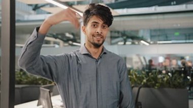 Gülümseyen Arap ofis müdürü öğrenci işvereni kameraya bakıp el hareketini davet ediyor ve hoş geldin işareti kullanarak selam veriyor.